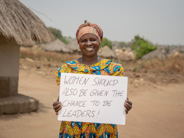 Loyce holds a sign advocating for women's rights in Sierra Leone