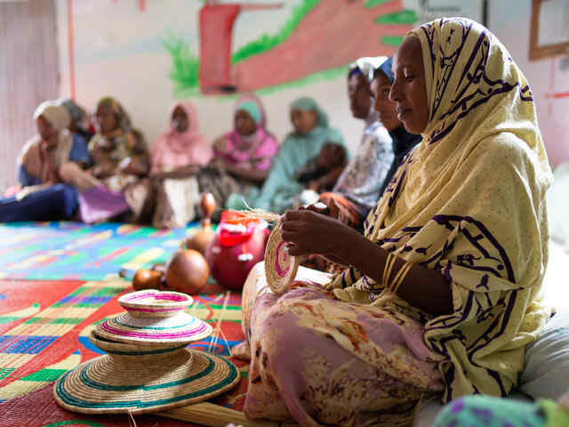 Eine Frau knüpft einen Korb.