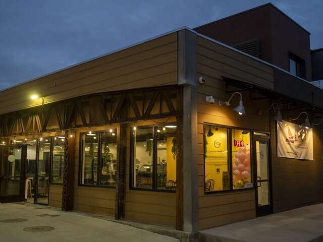 Exterior of the Spice on 9th Cafe building at dusk, lights shining out of a building wrapped in windows.