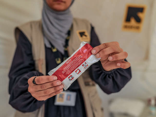 En näringsspecialist håller upp en nötkrämsklämmis som används vid behandling mot undernäring.