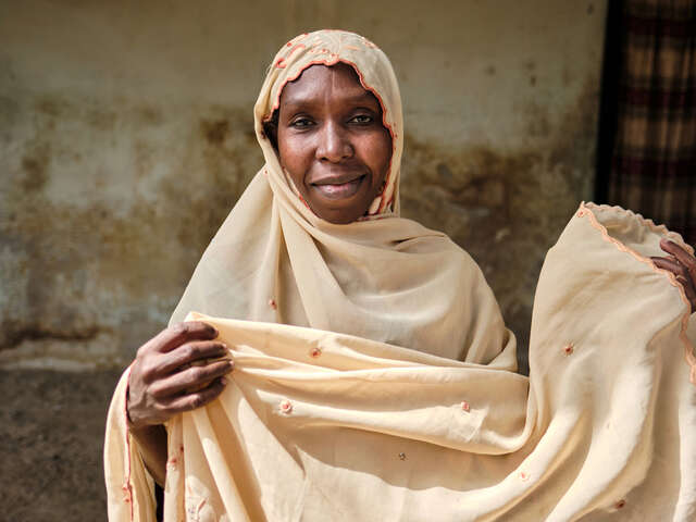 En kvinna står framför en husvägg.