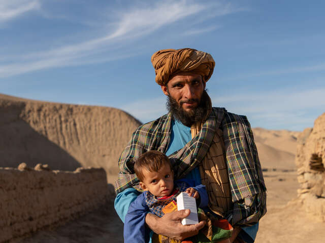 Pappa bär sin son och mediciner i famnen, i torkdrabbade Afghanistan. De har fått hjälp via RESCUE:s näringsprogram.