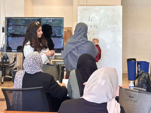 SHC teacher encouraging student at white board.