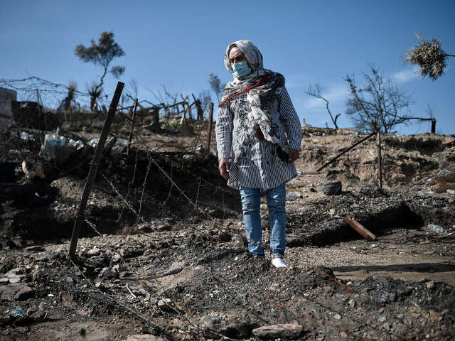 En kvinna går i ett nedbrunnet flyktingläger på Lesbos, Grekland.