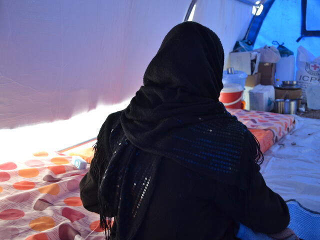 Alina kneels on the ground in a tent at a camp for displaced families outside Mosul.
