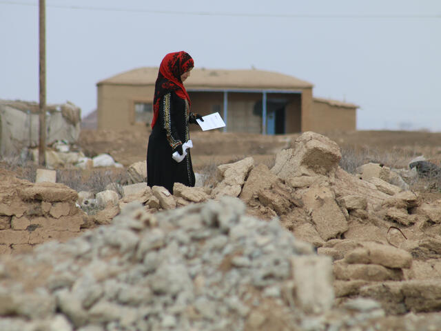 A woman picks her way through the rubble of her village in northeastern Syria.