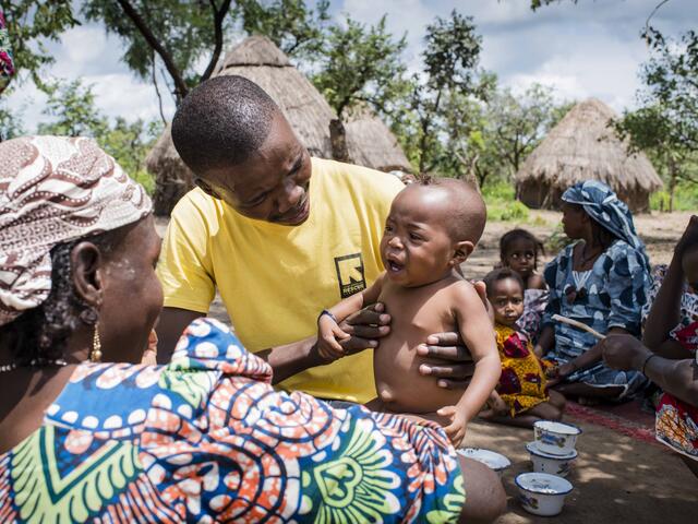 An IRC health worker examines a young child suffering from malnutrition as people return to their village after fleeing fighting.