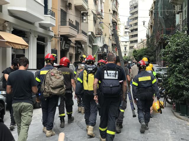 A group of Beirut firefighters responding to the explosion walk down a street