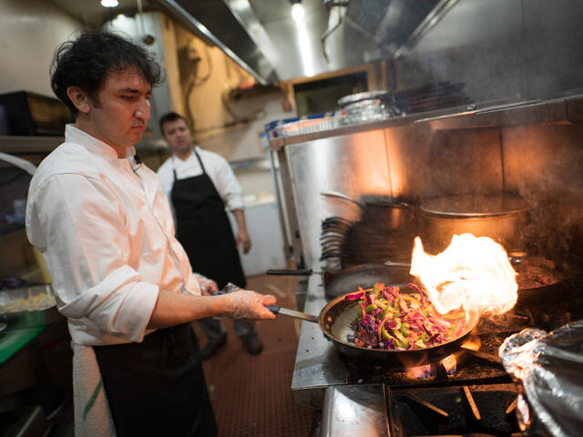 A chef from Afghanistan sautees vegetables in a skillet over a high flame at his restaurant in Virginia.