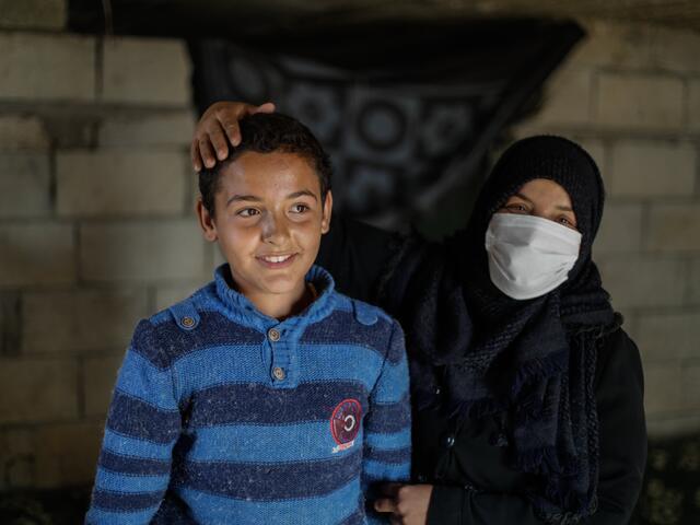 Tareq and his mother, Muna, in their home. She is holding his arm and has her hand affectionately resting on his head.