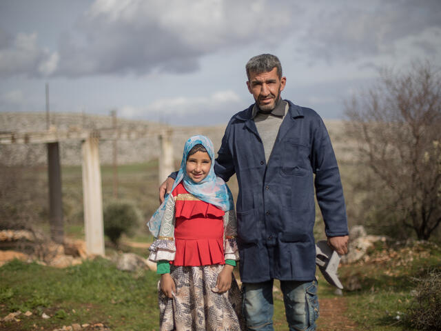 Sara and her father, Emad, stand outside. He has his arm around her and they are both looking at the camera.