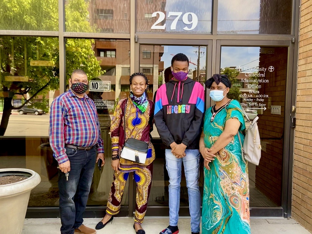 Naomi and Nasse stand with their father (on the left) and mother (on the right), wearing colorful clothing and smiles.