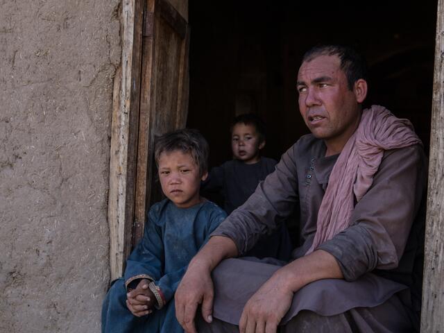 Abdul, 30, sits in a doorway with his children: Mujib, 1, Ismail, 3 and Ibrahim, 5.
