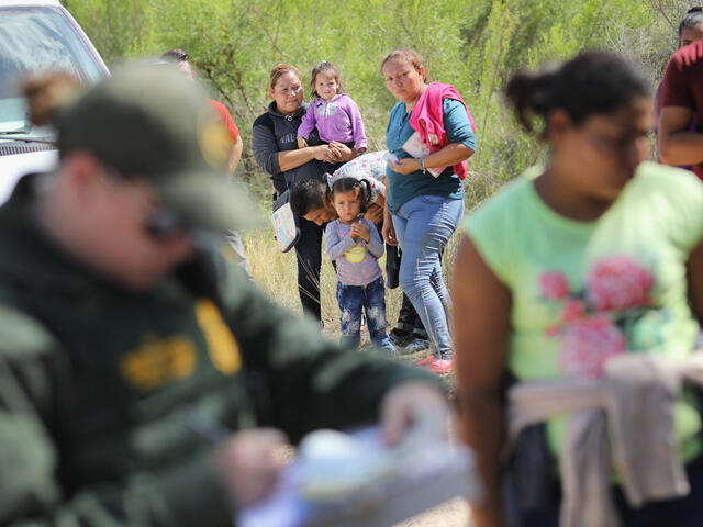 Central American asylum seekers wait as U.S. Border Patrol agents take groups of them into custody near McAllen, Texas.