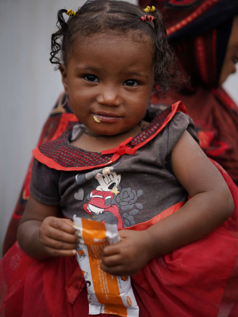 Ein kleines Mädchen wird von ihrer Mutter auf dem Arm getragen.