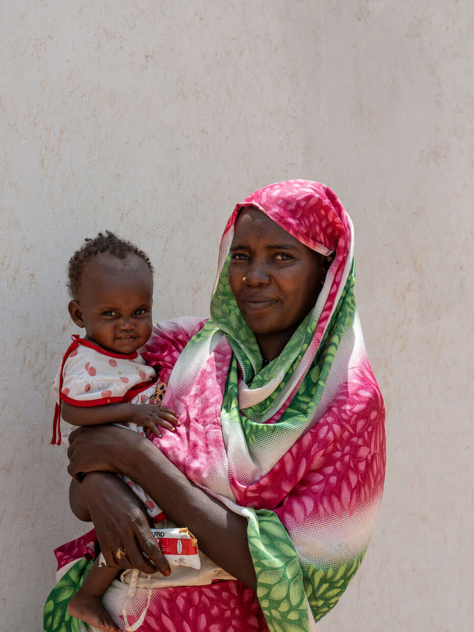 Mamma från Sudan med litet barn i famnen.