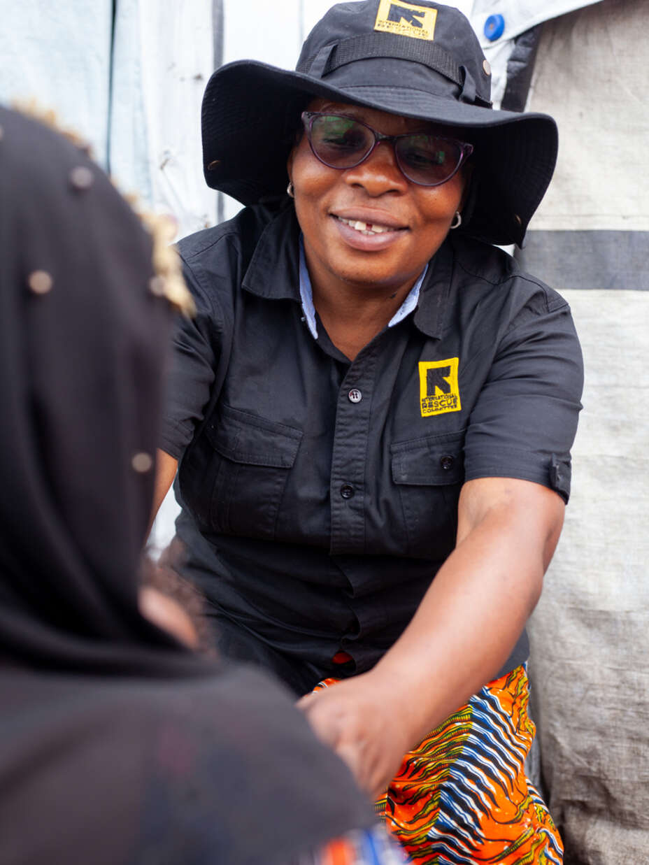 RESCUE:s personal i Kongo-Kinshasa pratar med en kvinna i ett flyktingläger, vars bakhuvud syns i bakgrunden.