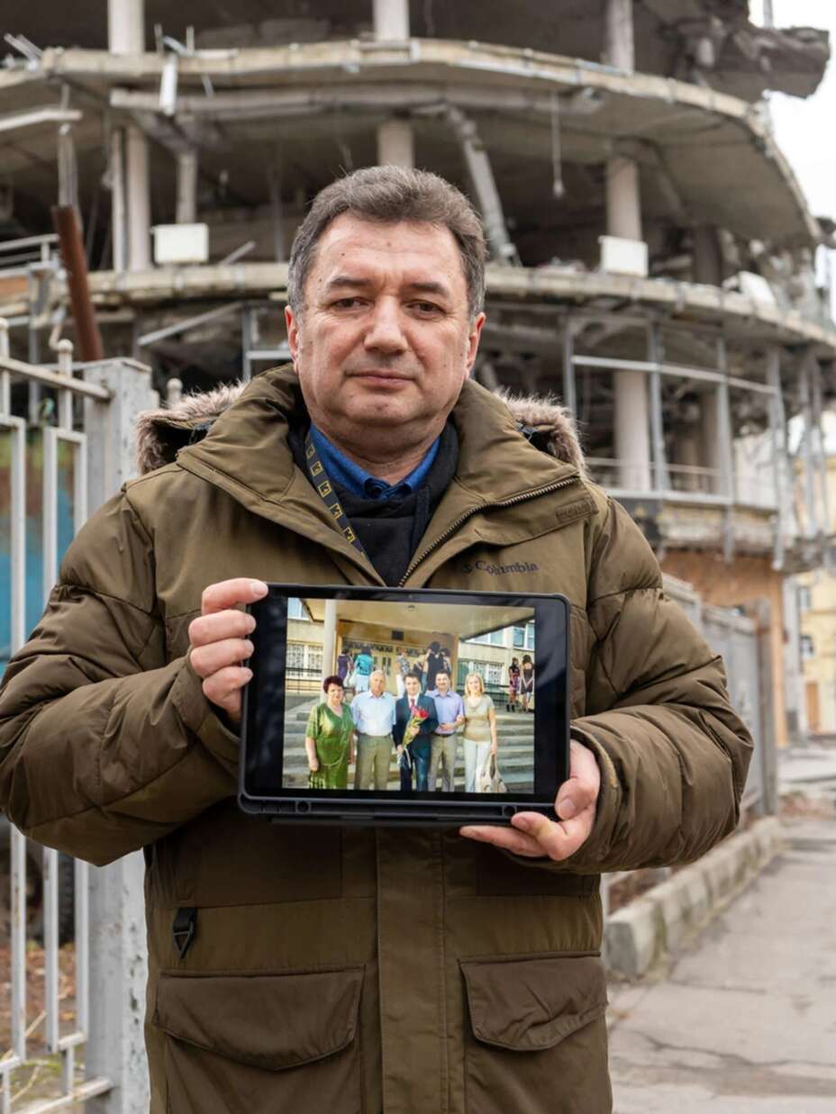 올렉 박사가 폭격으로 폐허가 된 건물 앞에서 전쟁 전 찍은 가족 사진을 보여주고 있습니다.