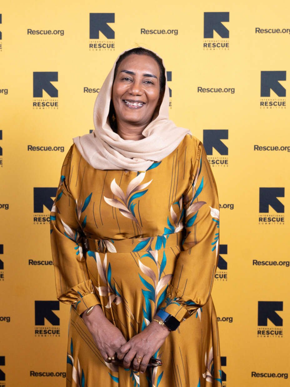 Eatizaz steht lächelnd vor einem IRC-Hintergrund und blickt in die Kamera.