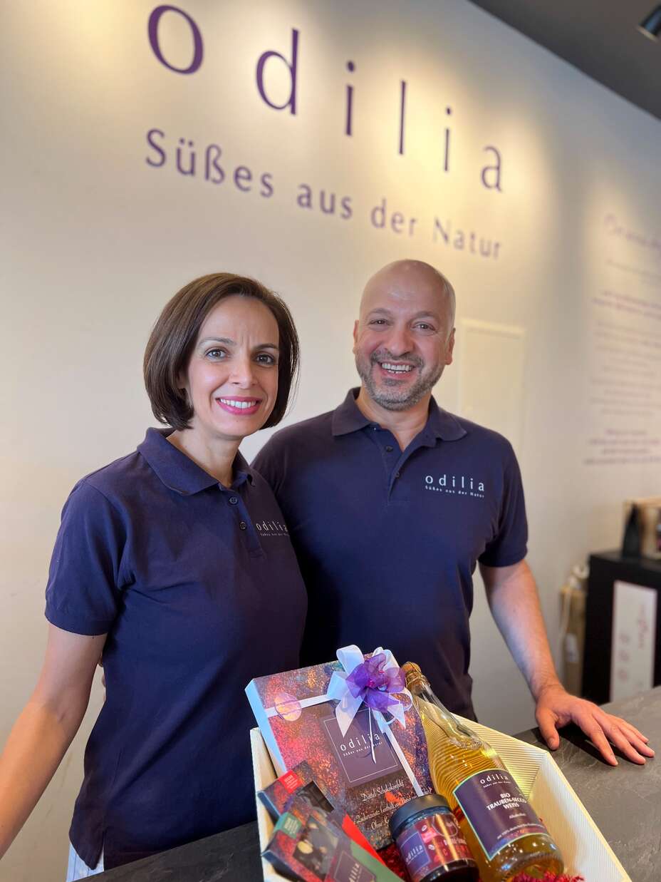 Zwei lächelnde Mitarbeitende in einem Geschäft mit einem Präsentkorb.