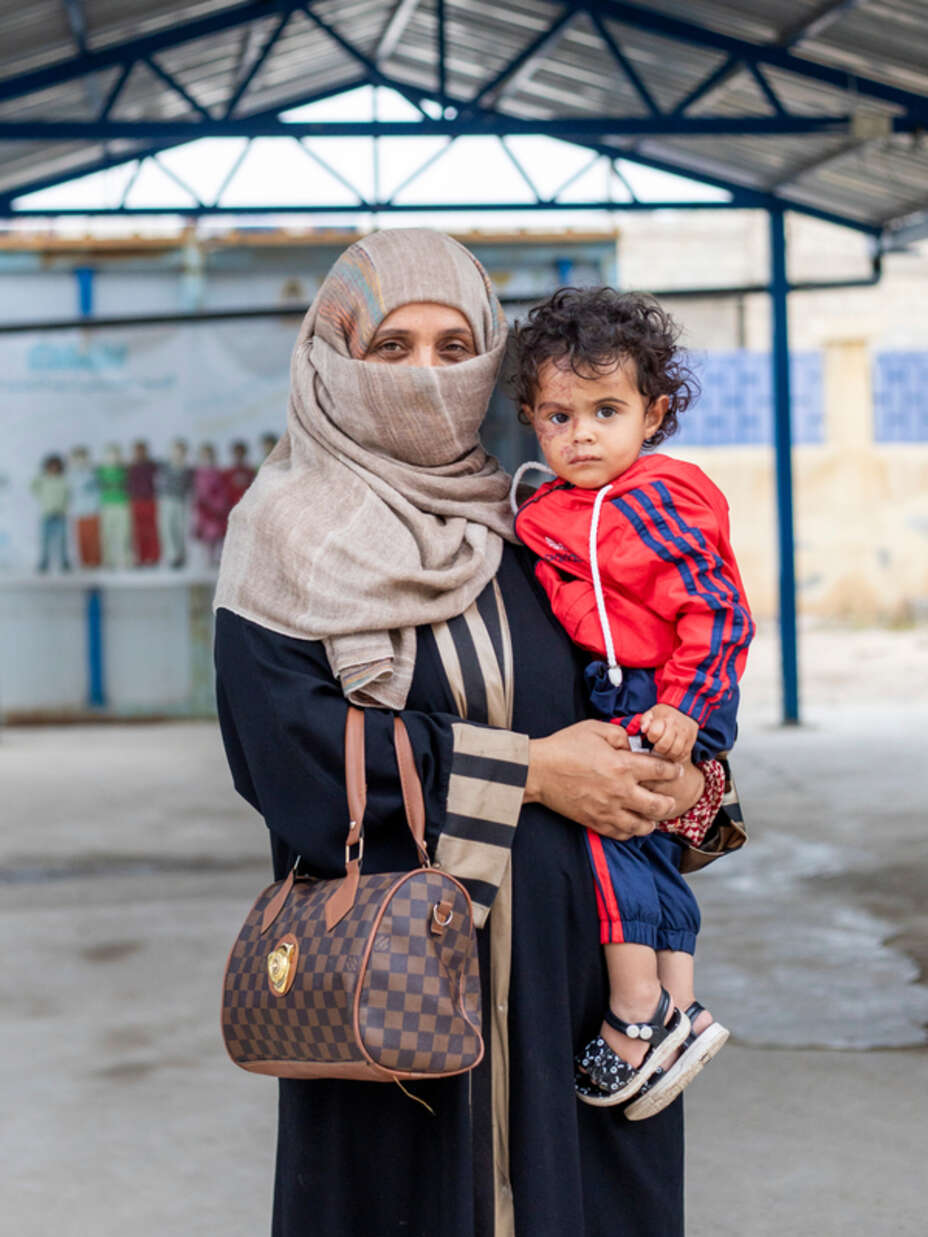 Rasha* står utanför RESCUE:s klinik med hennes dotter Jana*