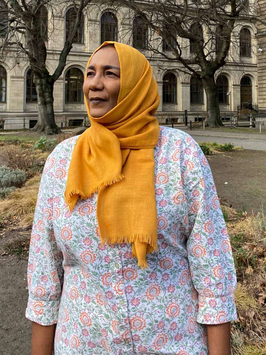 Eatizaz Yousif, IRC-Landesdirektorin in Sudan, steht vor einem Gebäude in Berlin und richtet den Kopf zur Seite.