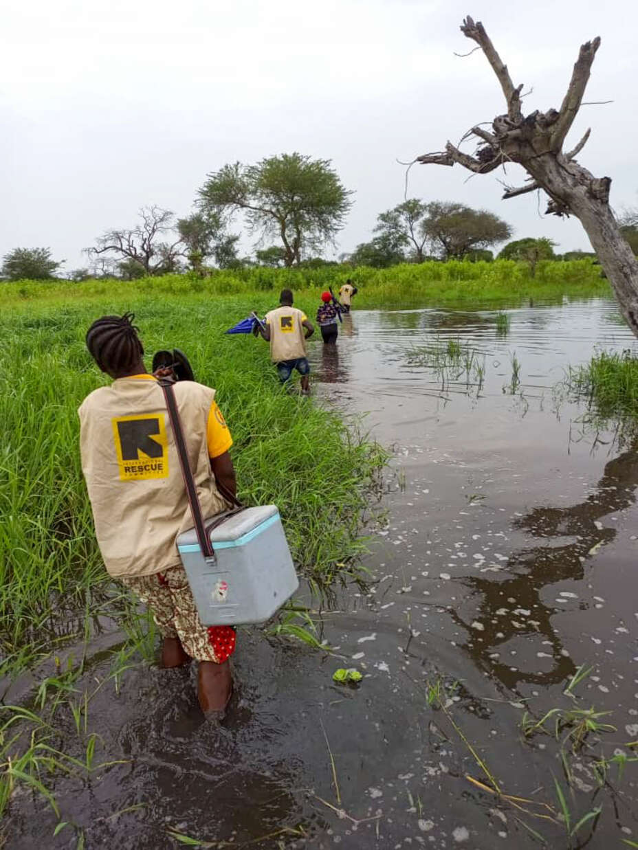 IRC staff in South Sudan traverse through a flooded village to reach children with vaccinations in Koch County.