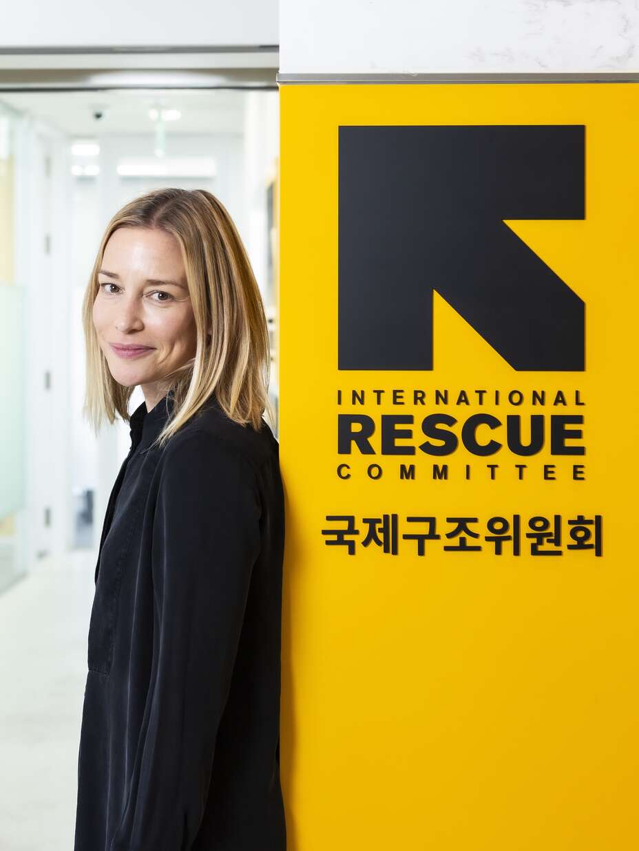 파이퍼 페라보 홍보대사가 한국사무소 간판 앞에 서서 포즈를 취하고 있습니다.