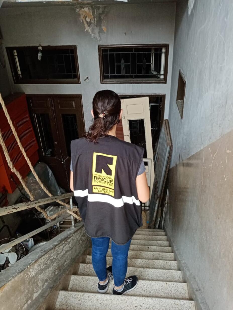 An IRC staff member on the stairway of Assad's building with its blasted-out windows and doors