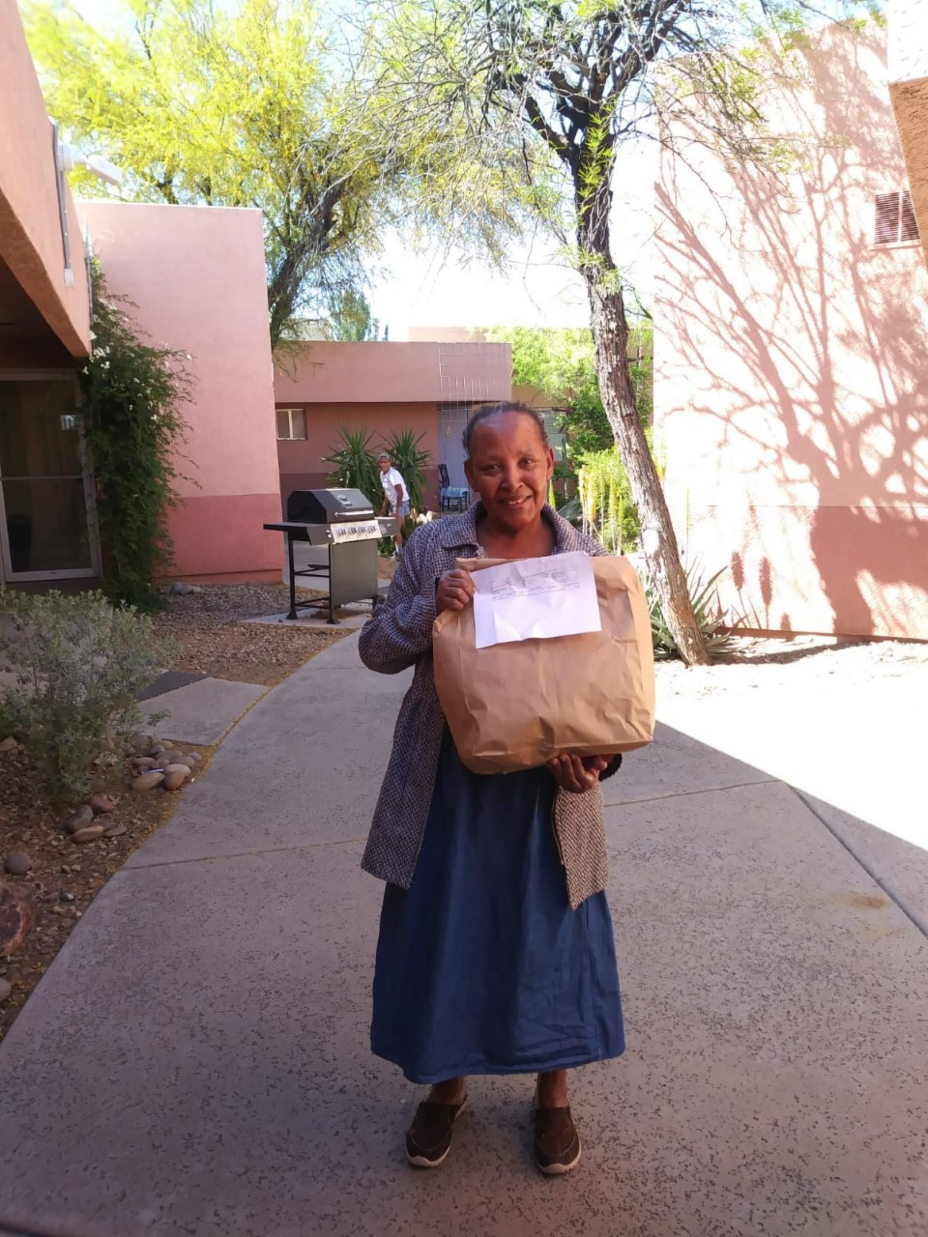An elder from Burundi holds a paper bag full of nutritious food provided by Pivot Produce. A weekly delivery of fresh produce means she can still eat the healthy food she's accustomed to and support local farmers while staying home during the pandemic.