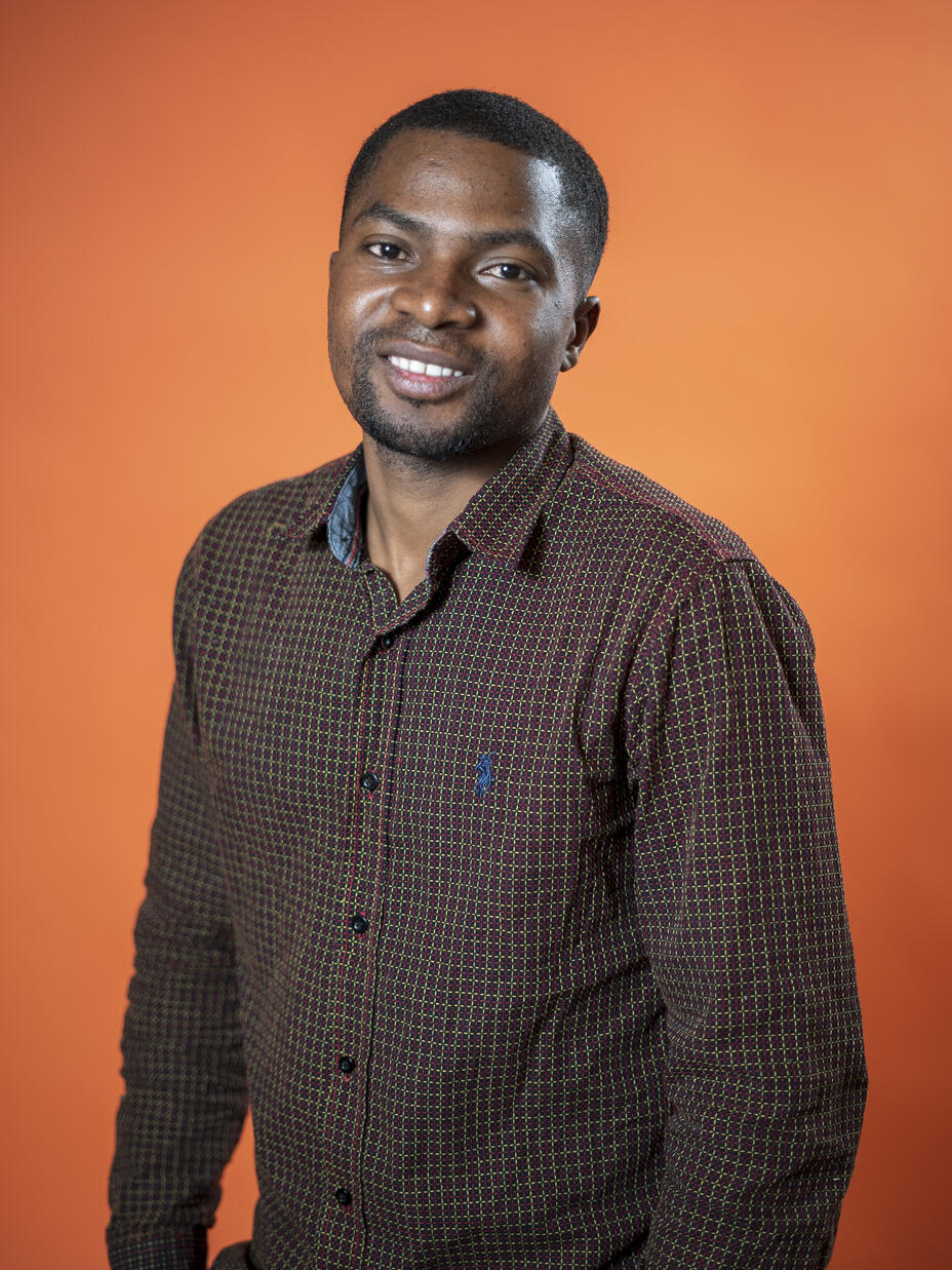 Robert Sebatware poses in front of an orange background 