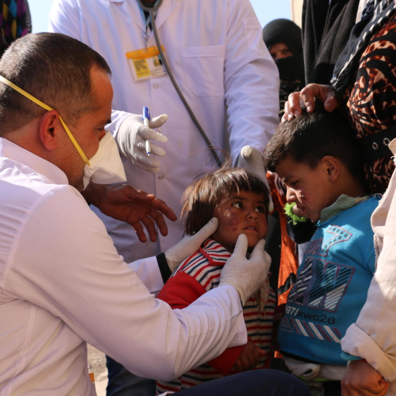 En RESCUE medarbetare undersöker ett barn och omges av andra barn.