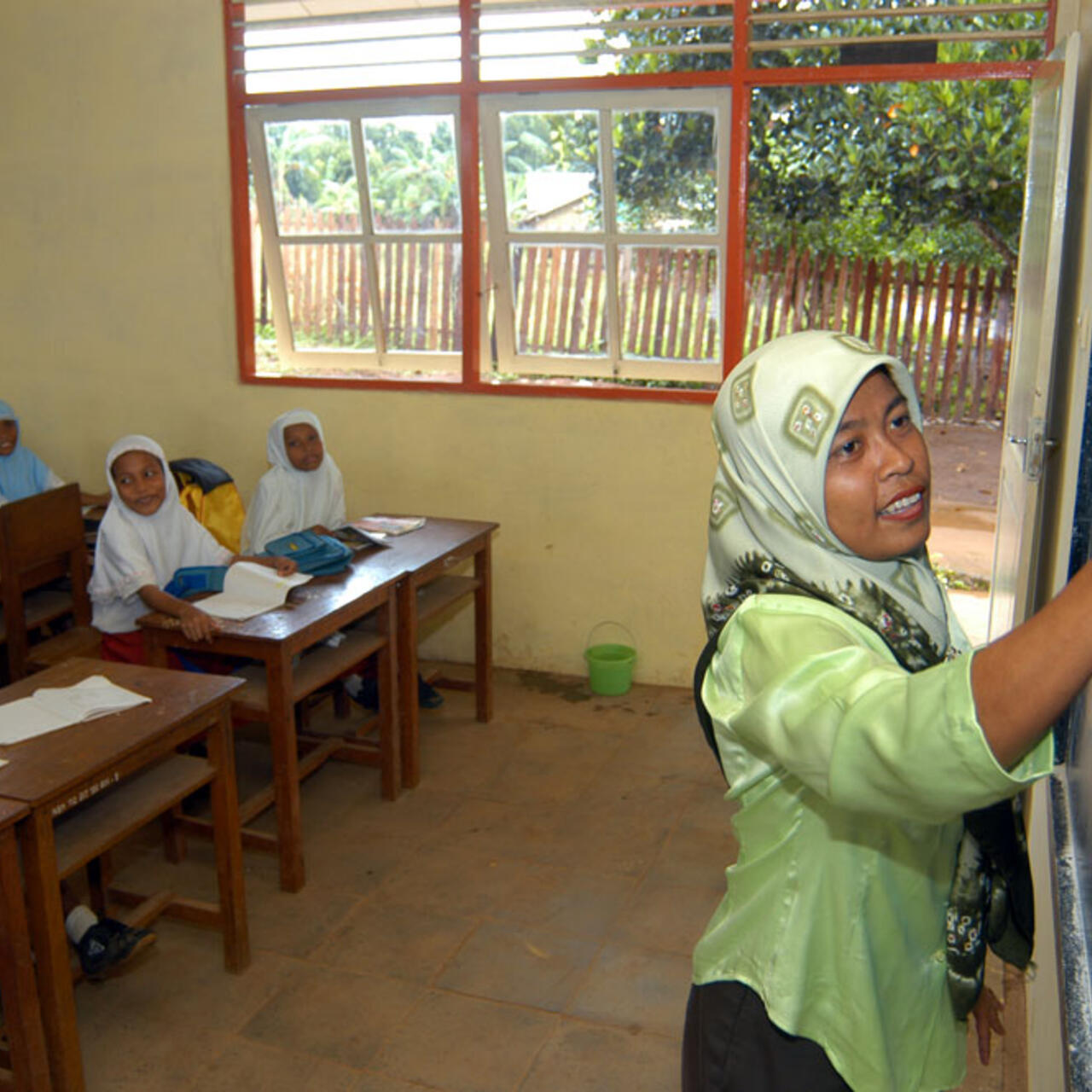 Eine Frau schreibt etwas mit Kreide an eine Tafel