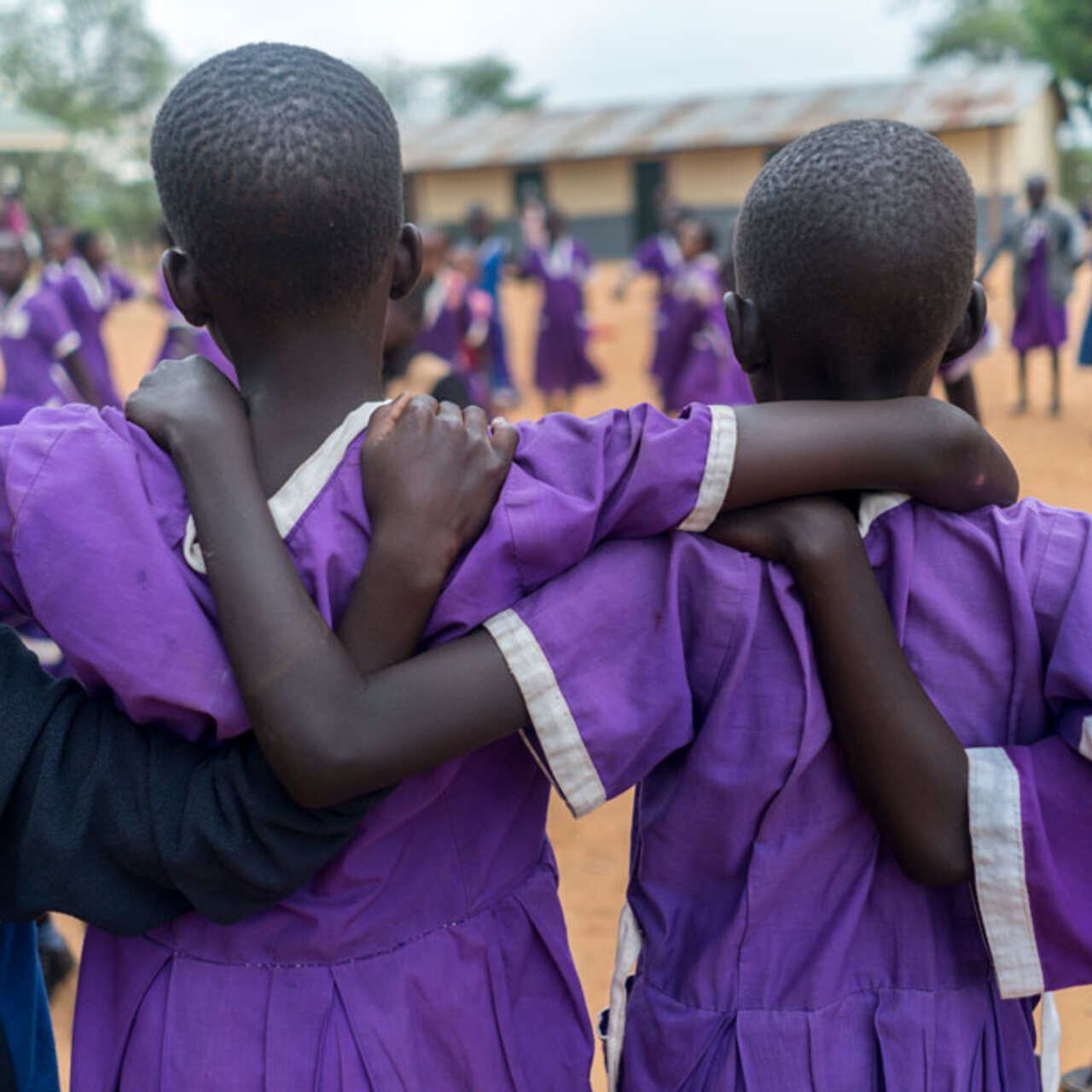Mädchen in lila farbenden Kleidern halten sich im Arm