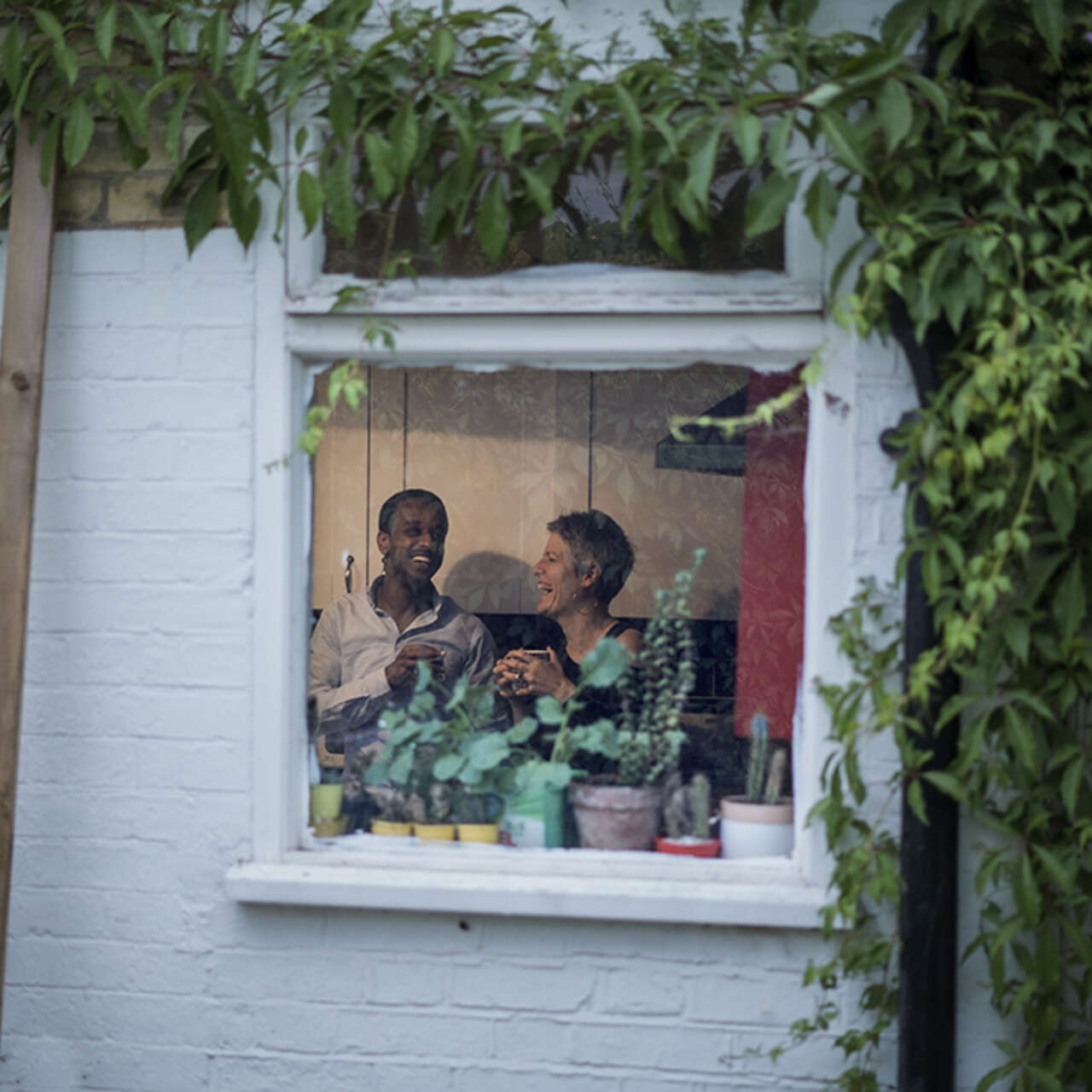 Ein Mann und eine Frau sitzen auf einer Couch durch ein Fenster fotografiert