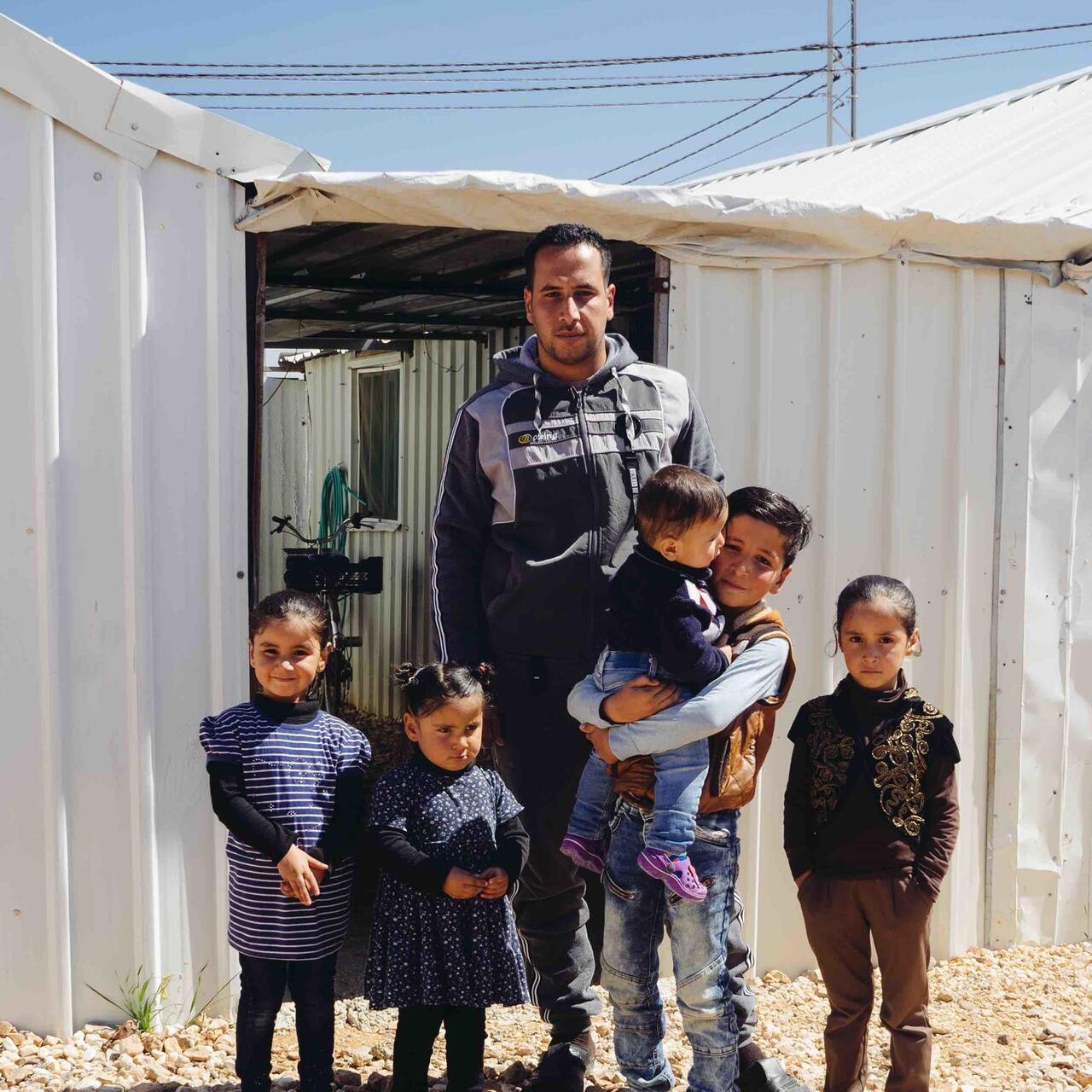 En familj står framför sitt tält