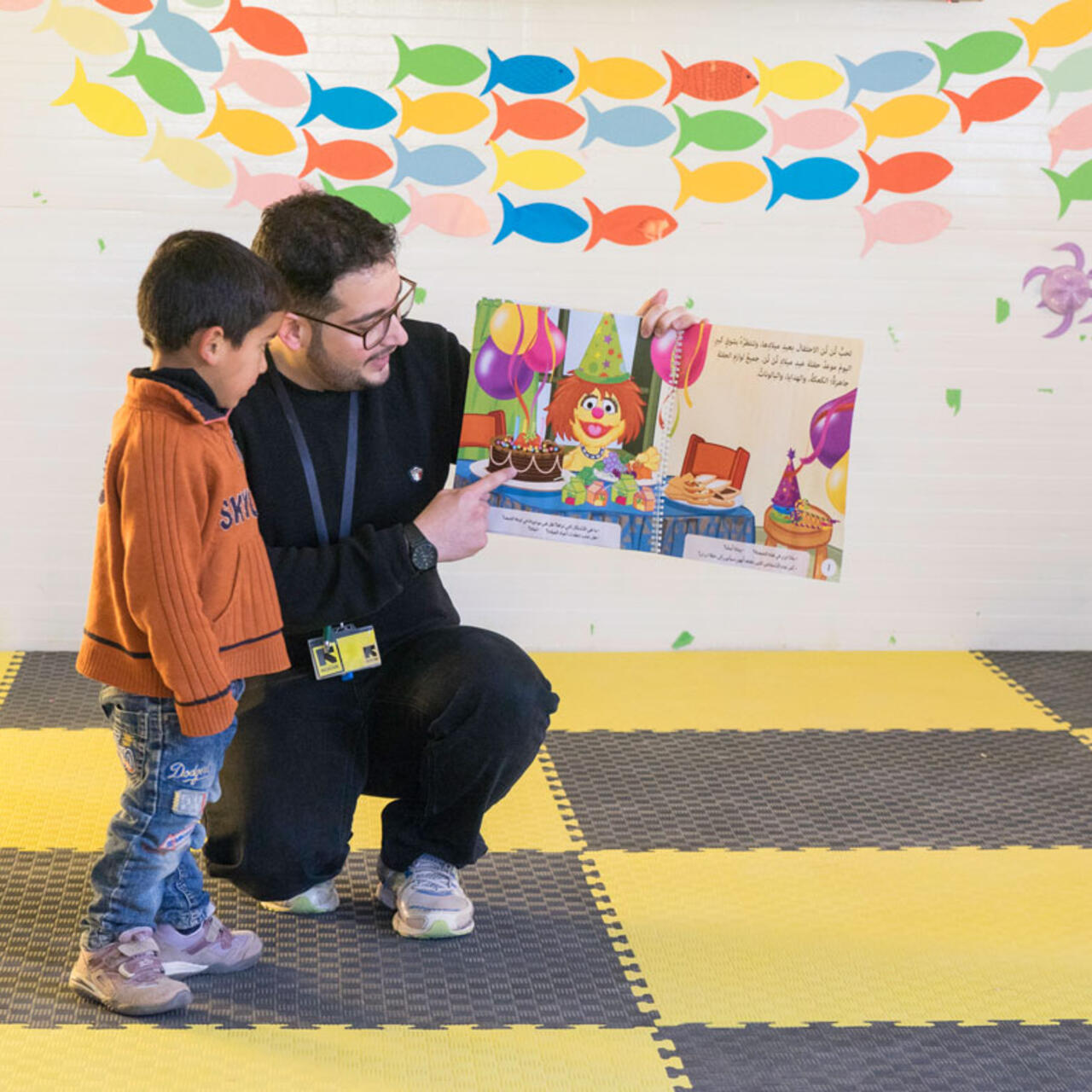 Ein kleiner Junge und ein Mann sehen sich zusammen ein Buch der Sesamstraße an.