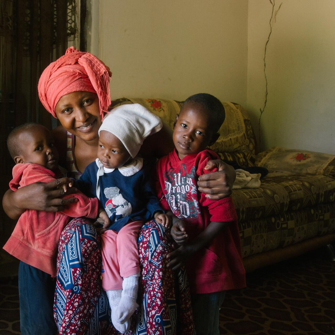 Jafiada sits with her three children on a sofa and smiles