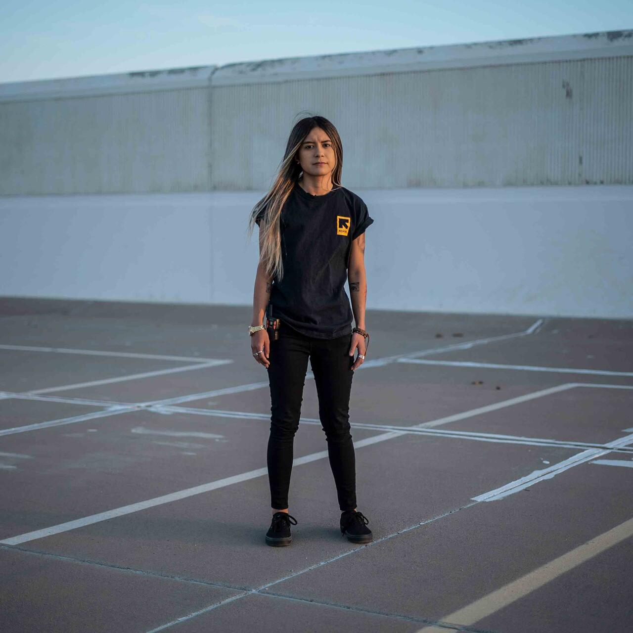 Die 21-jährige Alex Cruz steht selbstbewusst auf einem Parkplatz