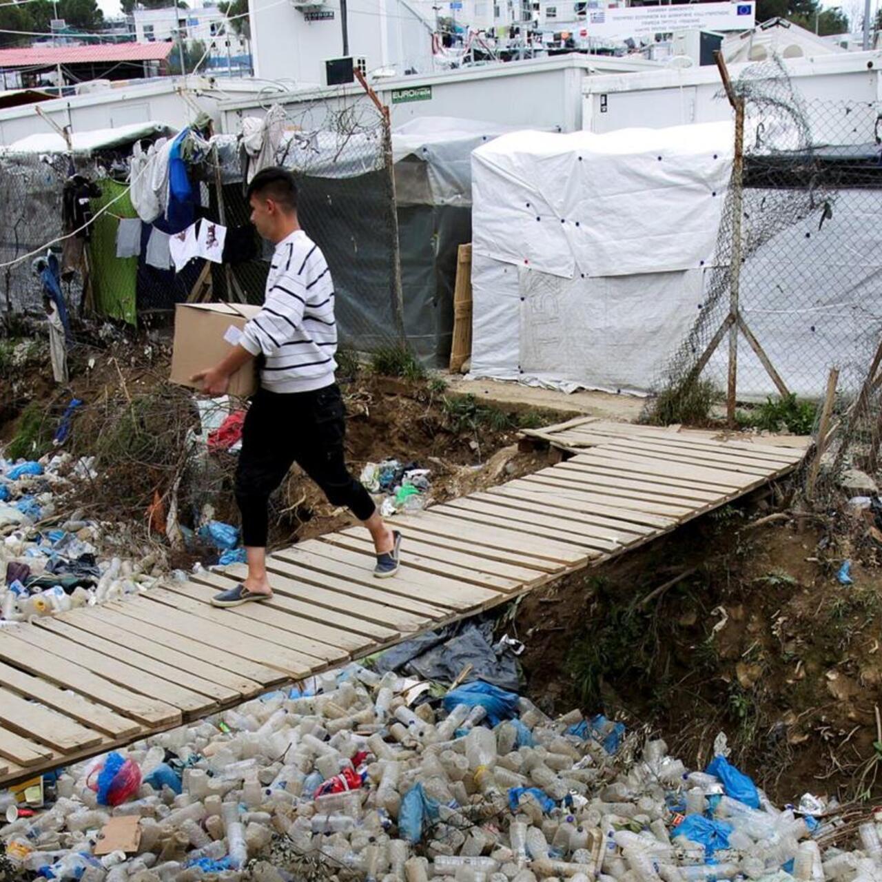 Ein Mann trägt eine Kiste über eine Brücke im Flüchtlingslager Moria