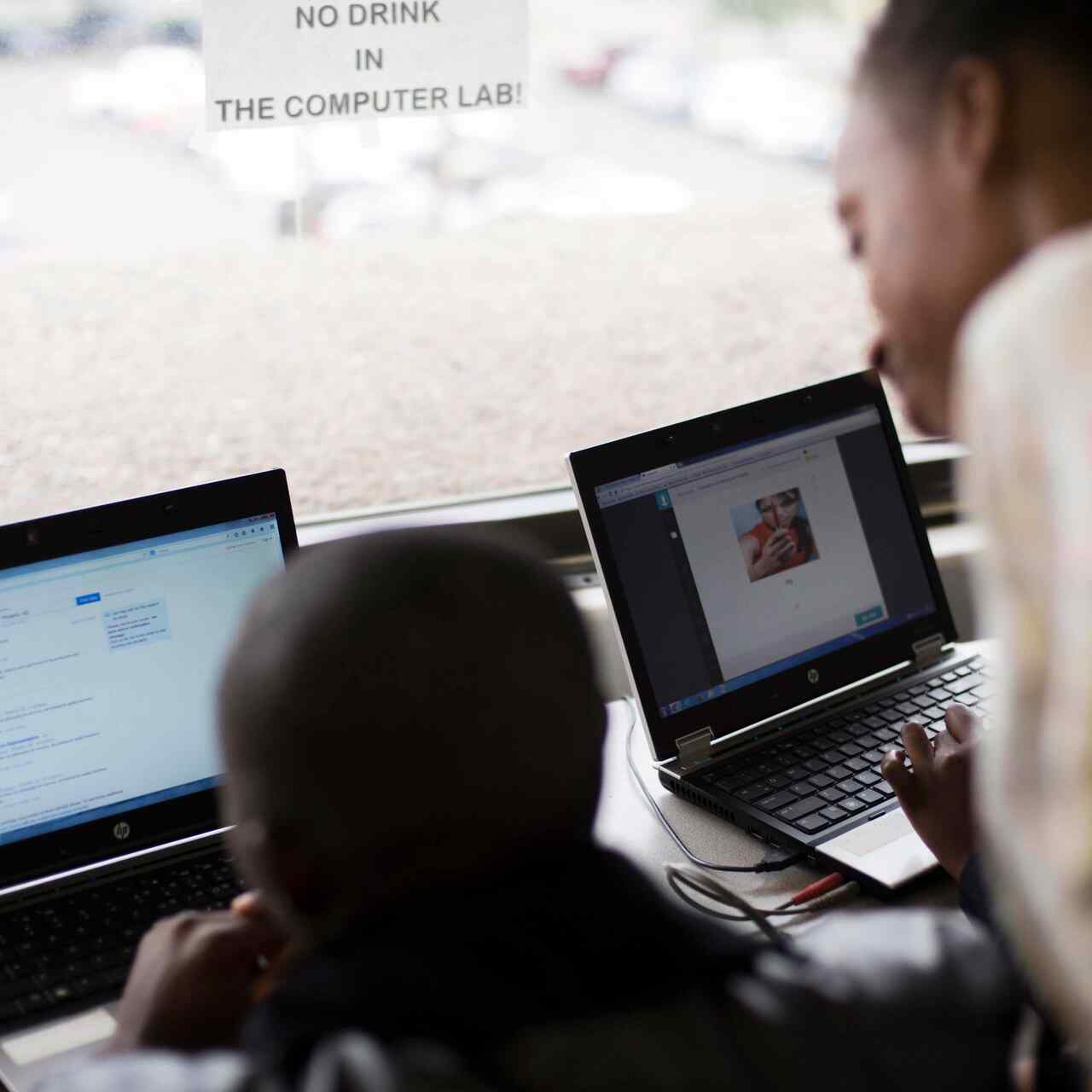 Ein Mann sitzt vor einem Computer, die Kursleiterin schaut über seine Schulter.