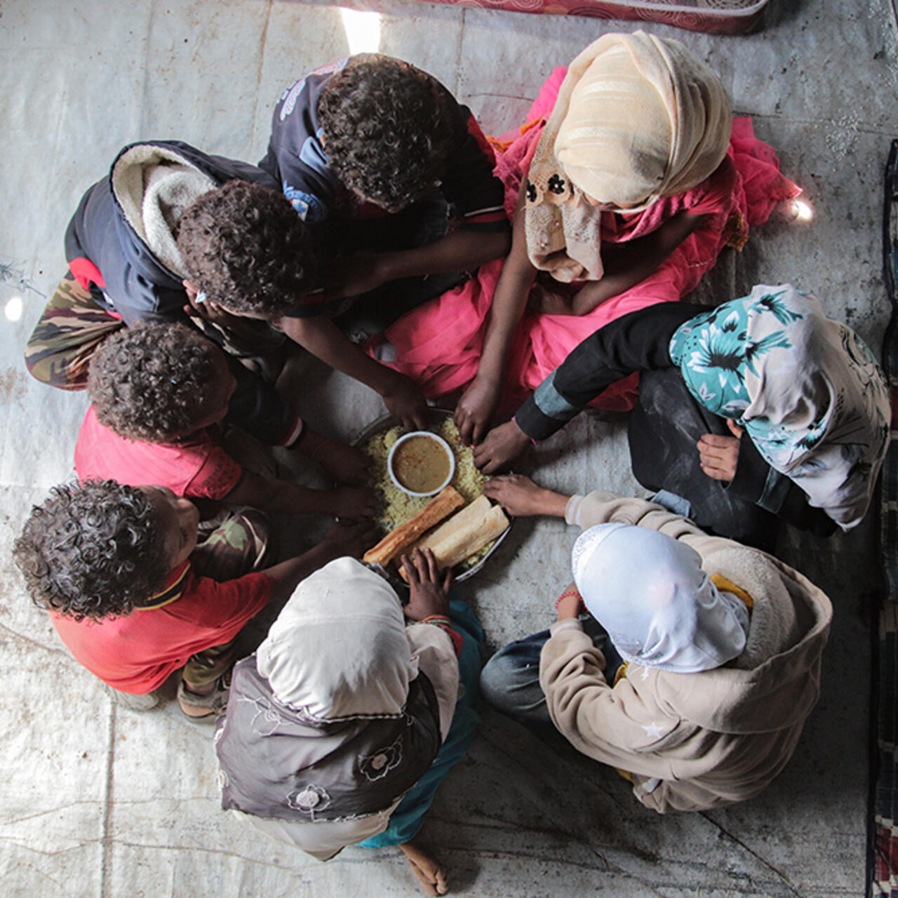 Kinder sitzen im Kreis und bereiten Essen zu.