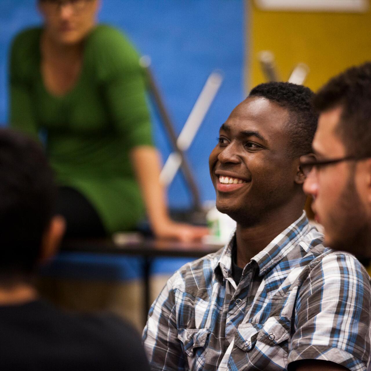 Zwei junge Männer schauen links aus dem Bild und lachen.