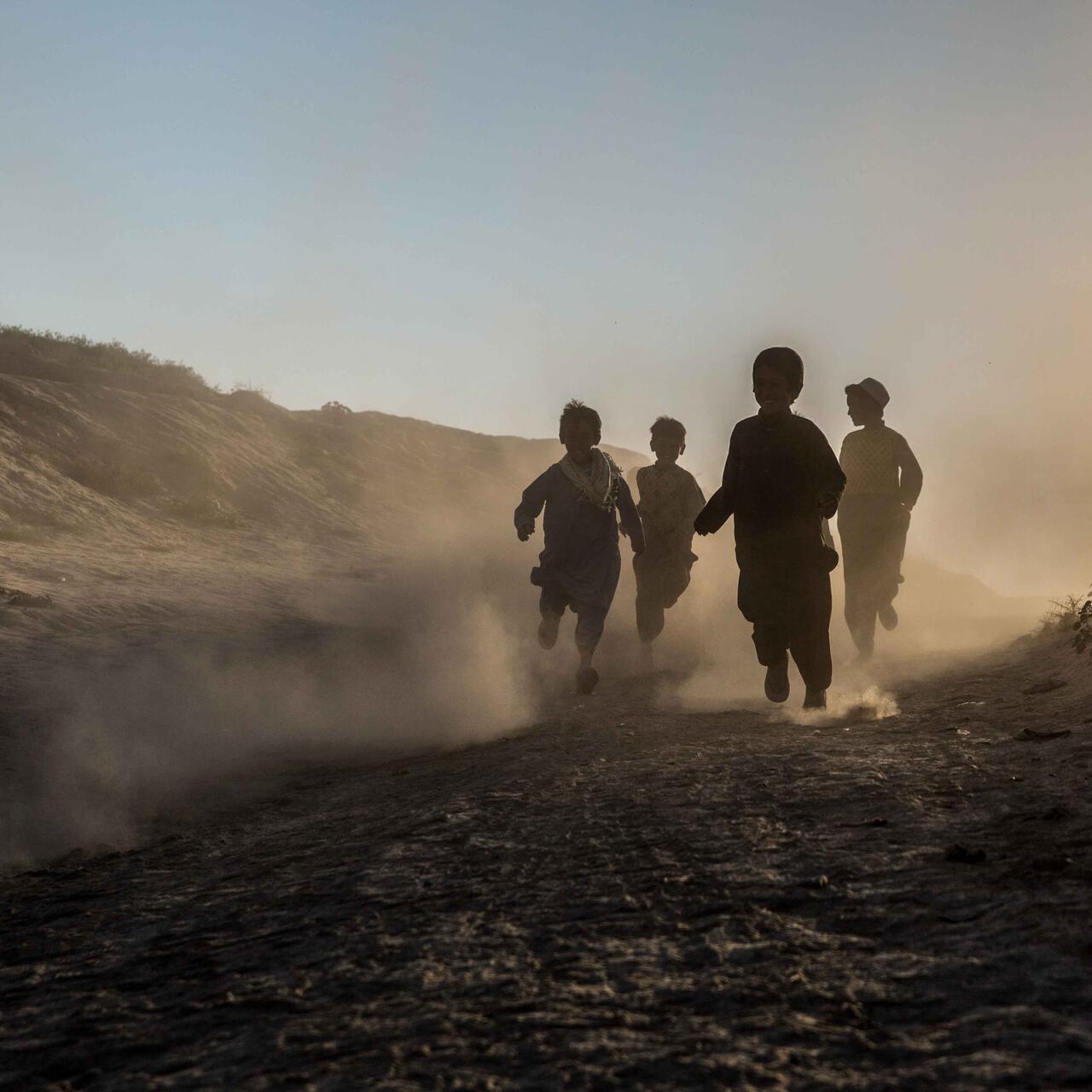 Kinder laufen durch Sand.
