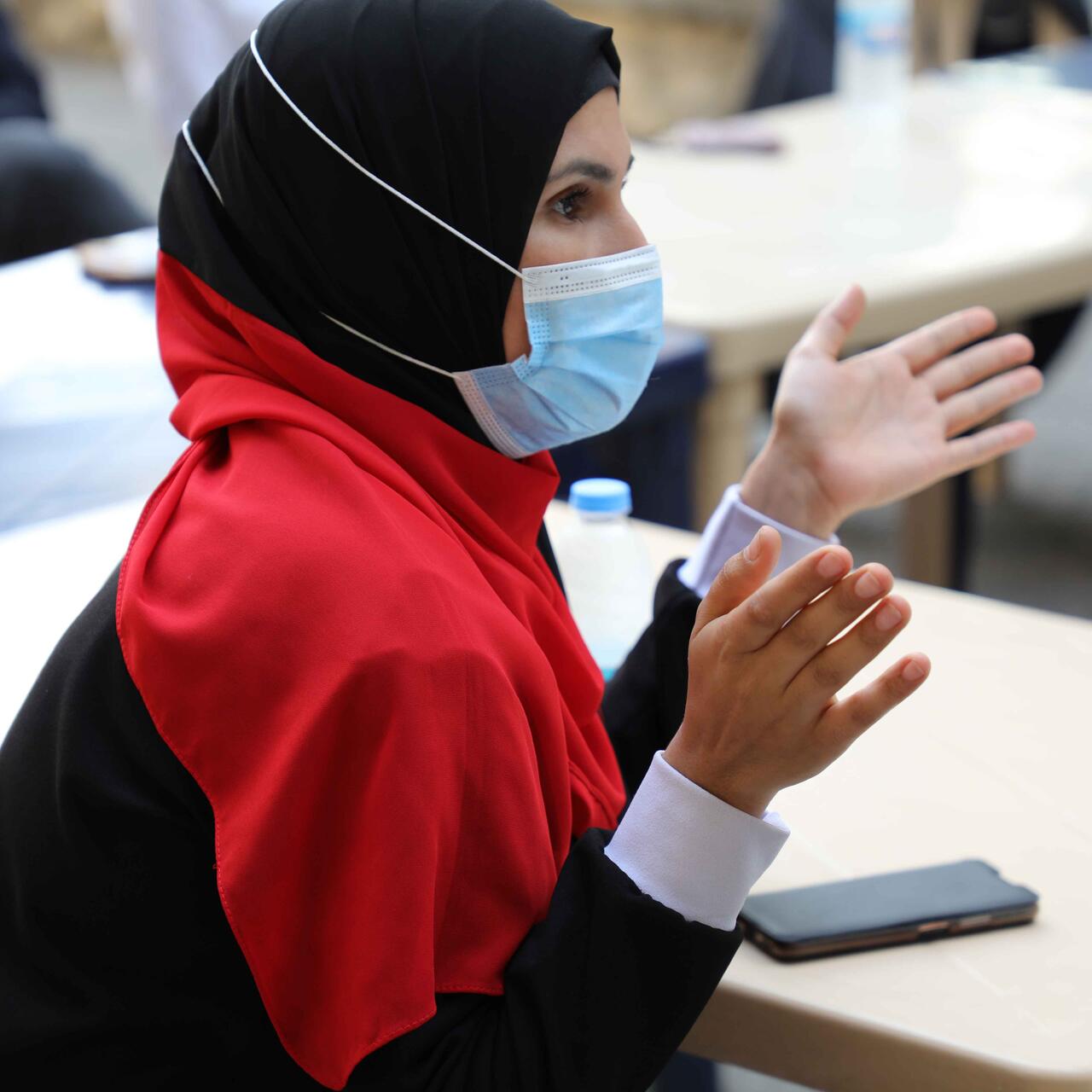 Sara sitzt an einem Tisch und redet