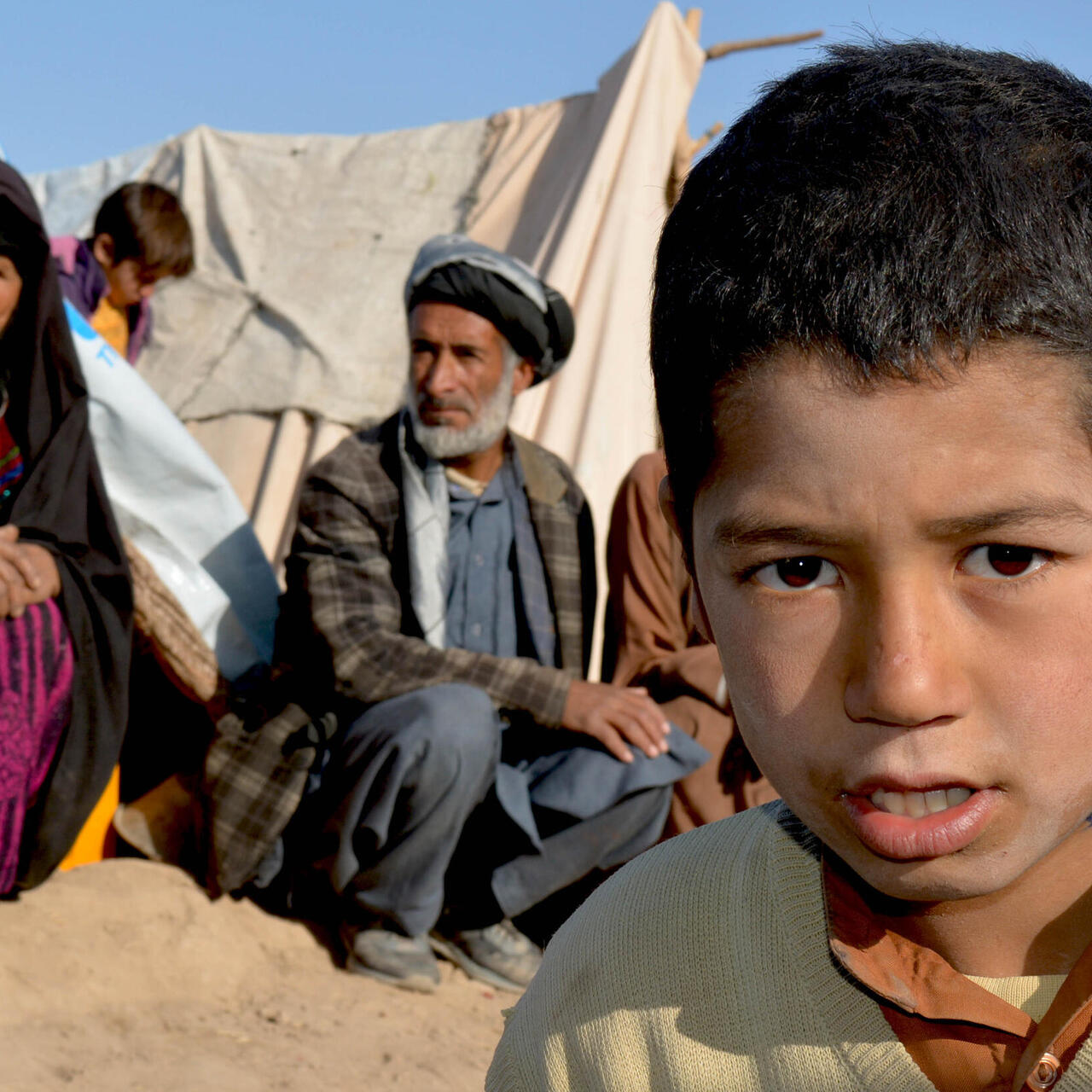 En familj på flykt i Herat, Afghanistan. Pojke tittar in i kameran.