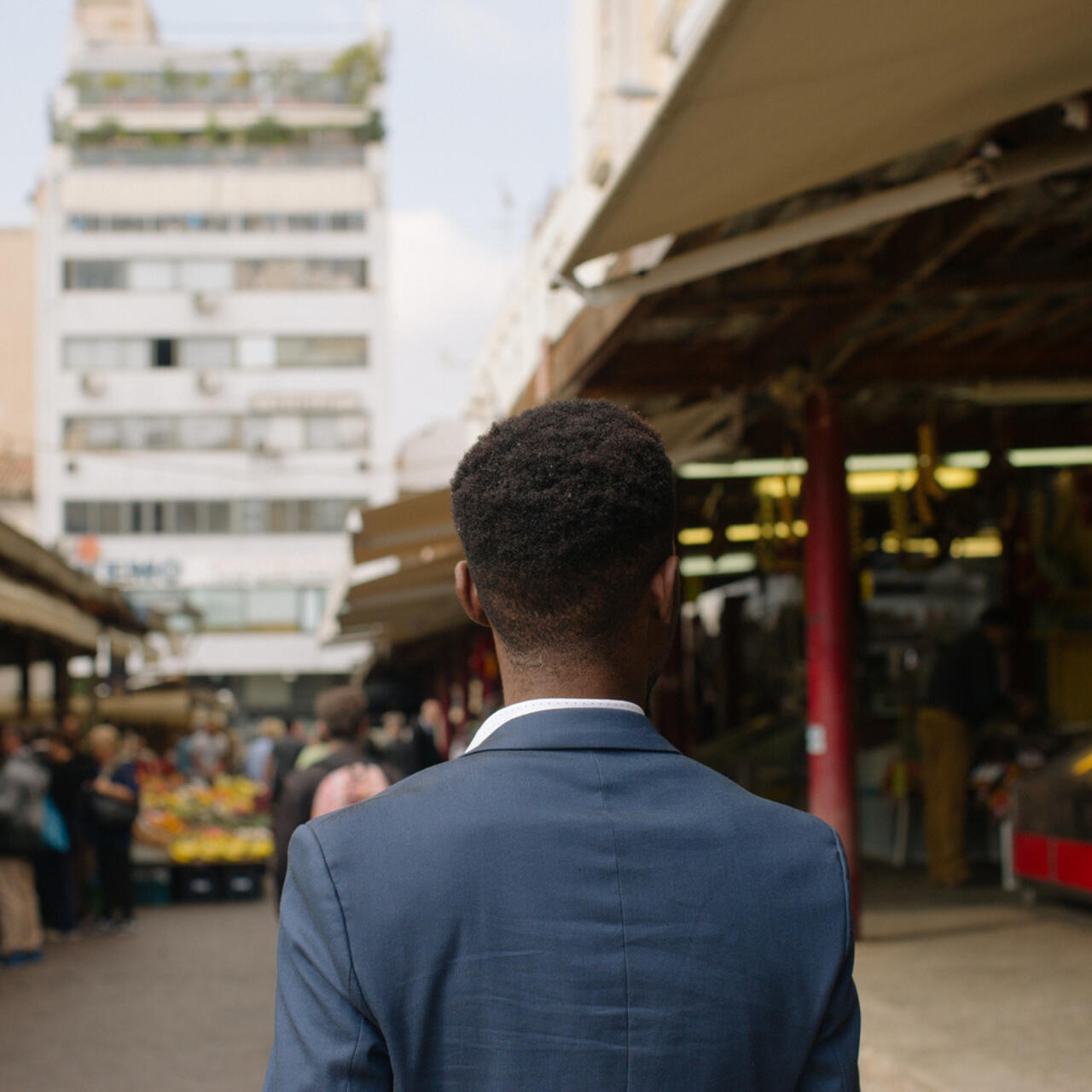 Moussa, a refugee from Ivory Coast, walks through a food market in Athens