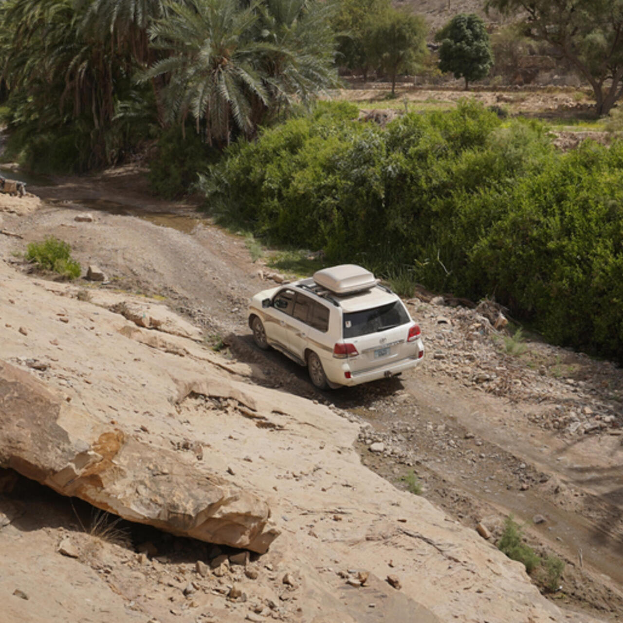 white car driving along a rocky remote road