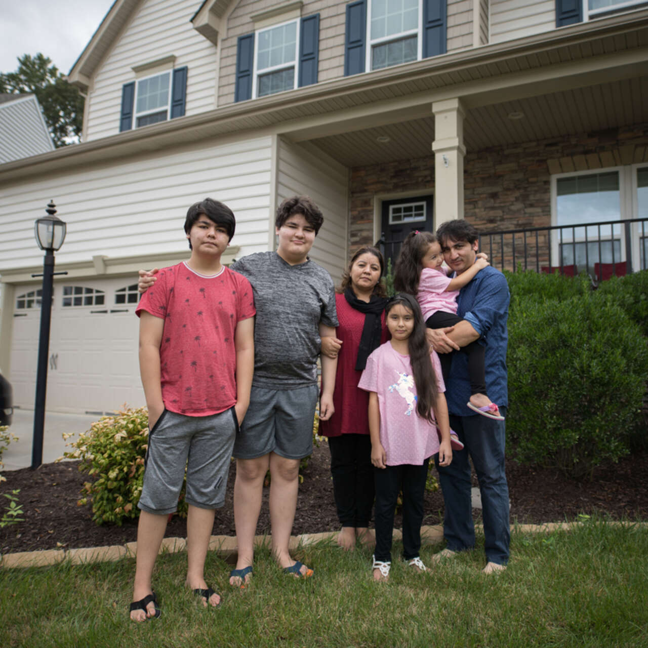 Photo of former Afghan refugee Noori standing outside his house with his family