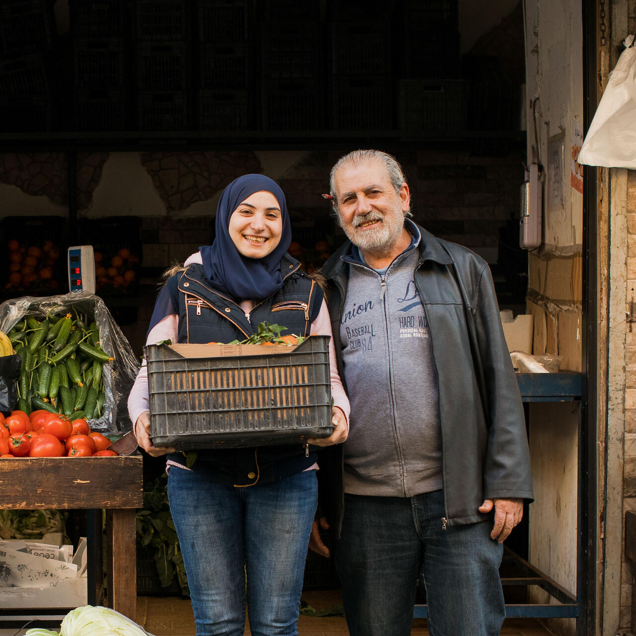 A woman and her father stand outside of their vegetable shop in Lebanon.